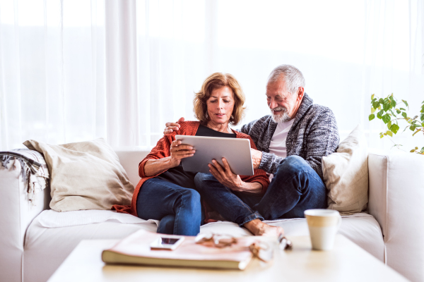 Happy senior couple with tablet relaxing at home.