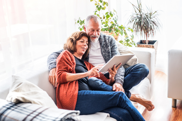 Happy senior couple with tablet relaxing at home.