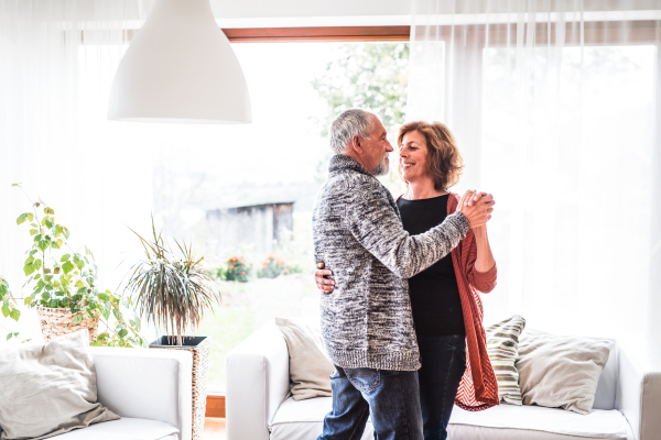 Happy senior couple relaxing at home, dancing.