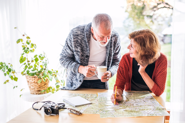 Happy senior couple with map at home, making plans.