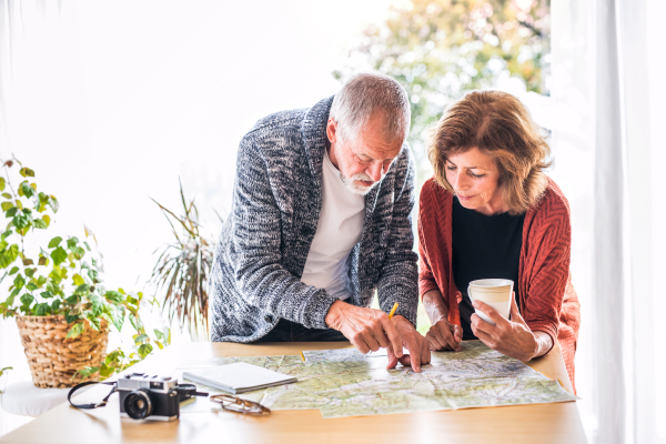 Happy senior couple with map at home, making plans.