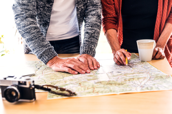 Unrecognizable senior couple with map at home, making plans.