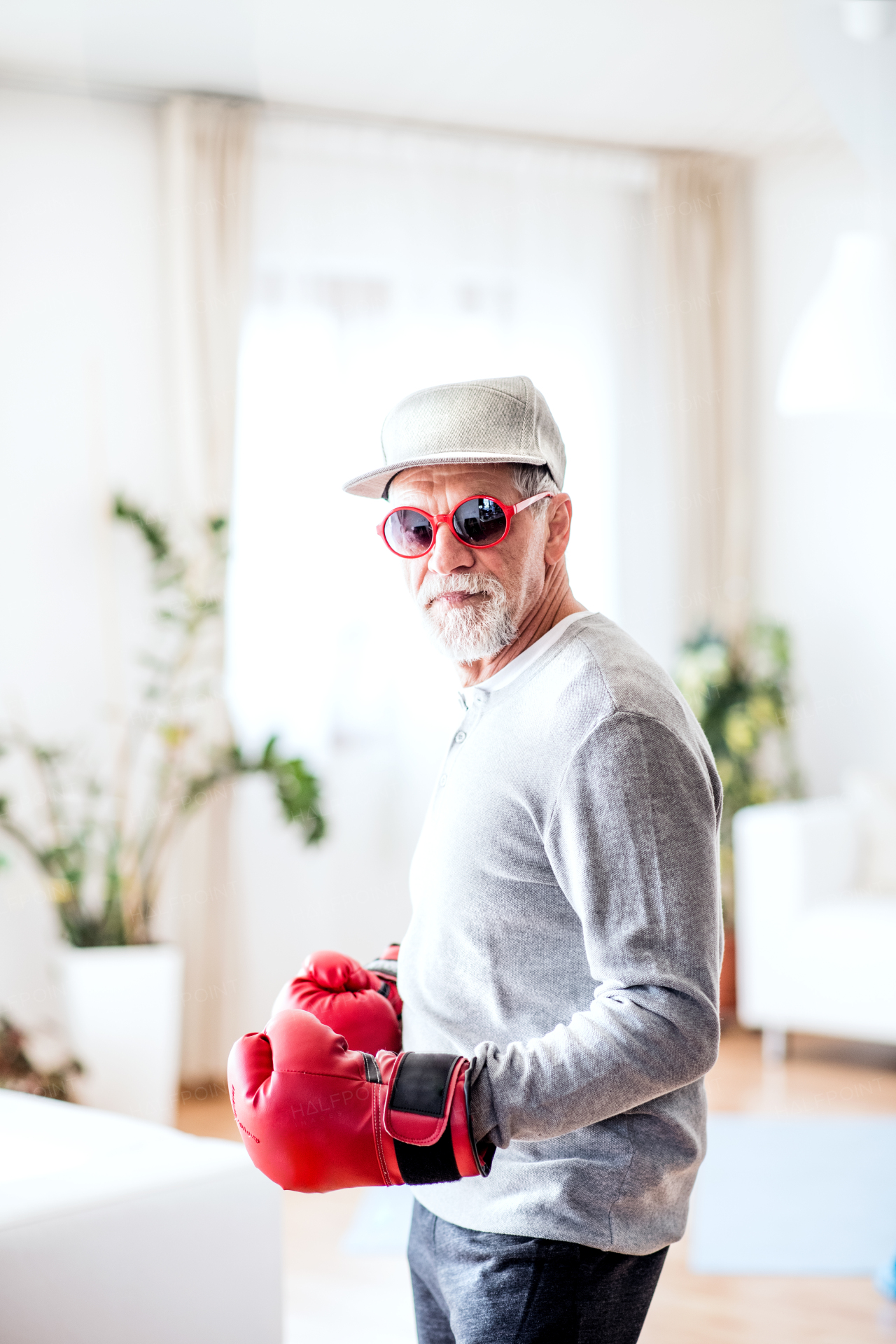 A crazy senior man with boxing gloves having fun at home.