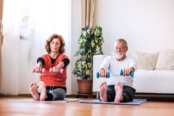 Happy senior couple doing exercise at home.