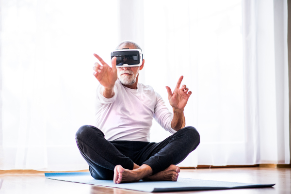 Active senior man with VR goggles doing exercise at home.