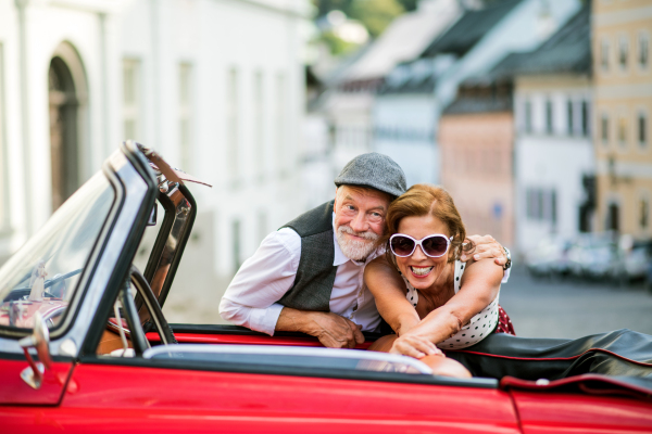 Elderly couple and vintage car on a roadtrip in city. Retired seniors enjoying free time and retirement.