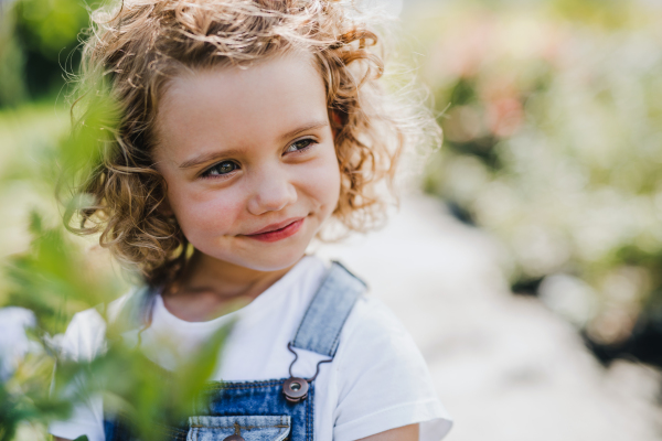 Portrait of cute small girl standing in the backyard garden. Copy space.