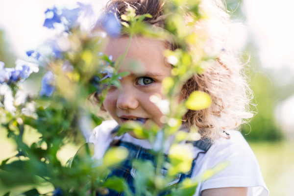 Portrait of cute small girl standing in the backyard garden. Copy space.