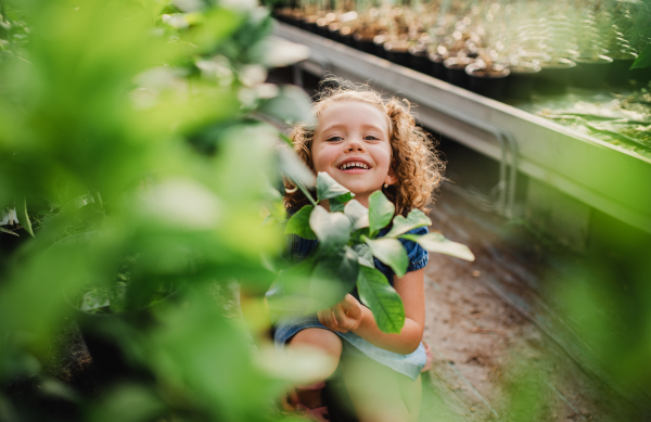 Portrait of cute small girl standing in the garden center. Copy space.