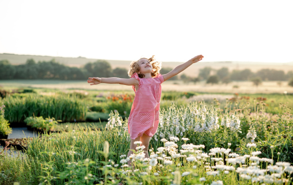 Cheerful small girl running in the backyard garden, having fun. Copy space.