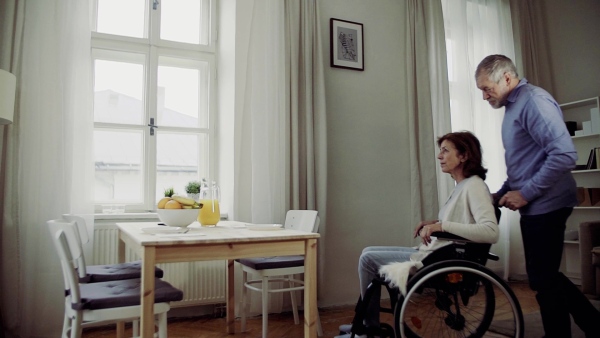 A senior couple in the morning at home, a man helping his disabled wife. Slow motion.