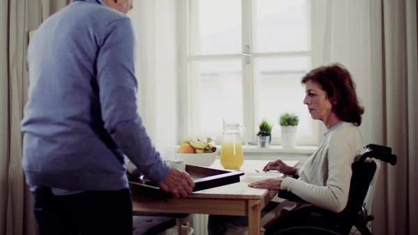 A senior couple with coffee sitting at the table at home, having breakfast.