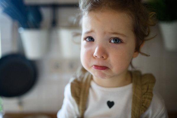 Small sick toddler girl indoors at home, looking at camera. Copy space.