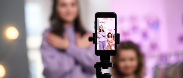 Portrait of sisters indoors at home, making video with smartphone. Lockdown concept.