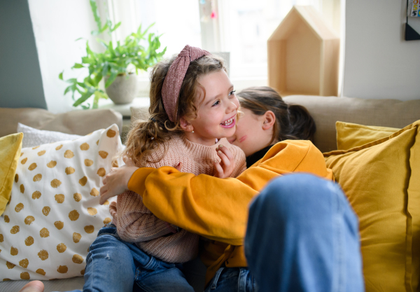 Cheerful sisters indoors at home, playing and having fun. Lockdown concept.