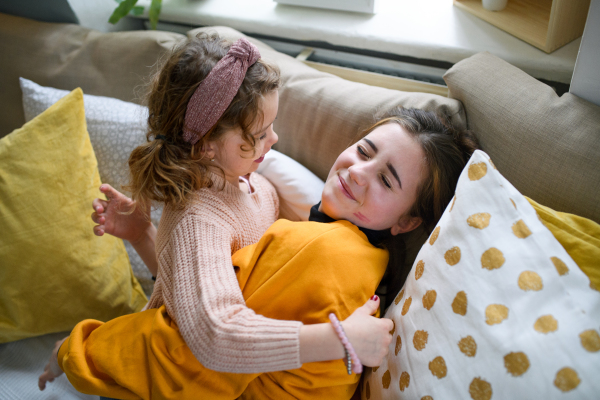 Cheerful sisters indoors at home, playing and having fun. Lockdown concept.