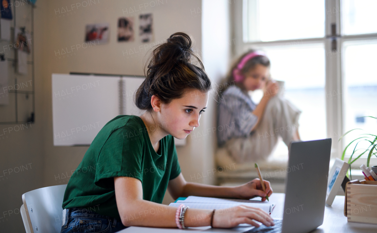 Teenager schoolgirl with face mask learning online indoors at home, coronavirus concept.