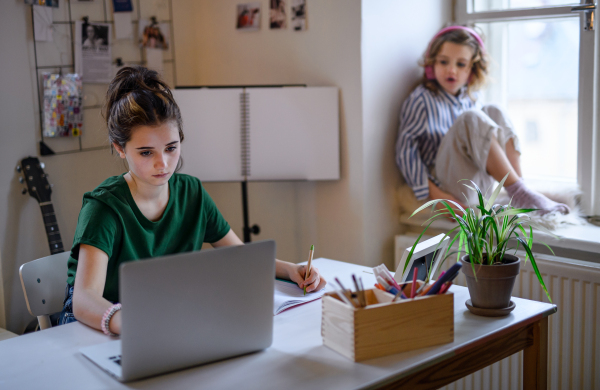 Teenager schoolgirl with face mask learning online indoors at home, coronavirus concept.