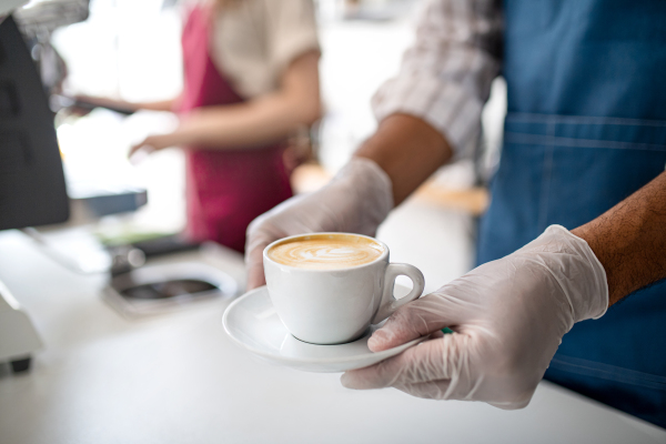 Obscured waiter serving coffee in cafe, small business, coronavirus and new normal concept, midsection.