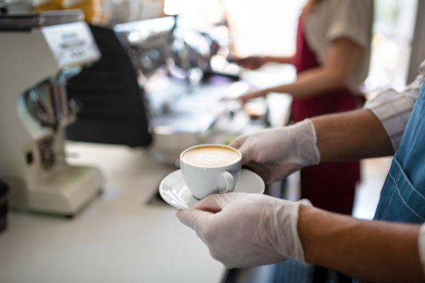 Obscured waiter serving coffee in cafe, small business, coronavirus and new normal concept, midsection.