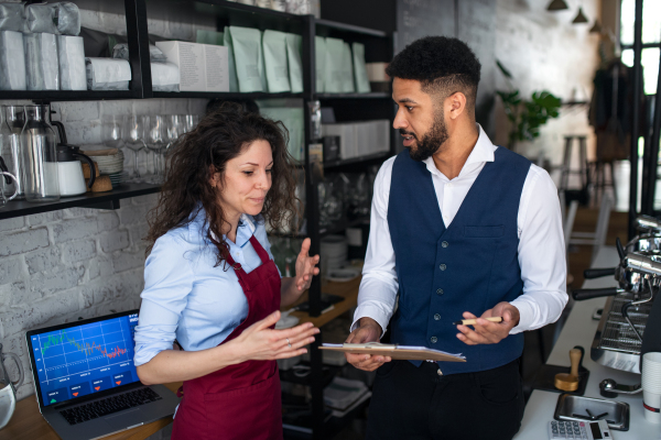 A coffee shop manager discussing issues with waitress in cafe, small business and new normal concept.