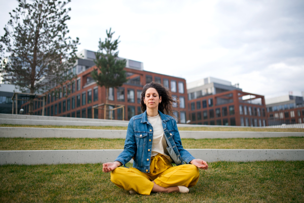 A portrait of woman doing yoga outdoors in park in city, eyes closed.