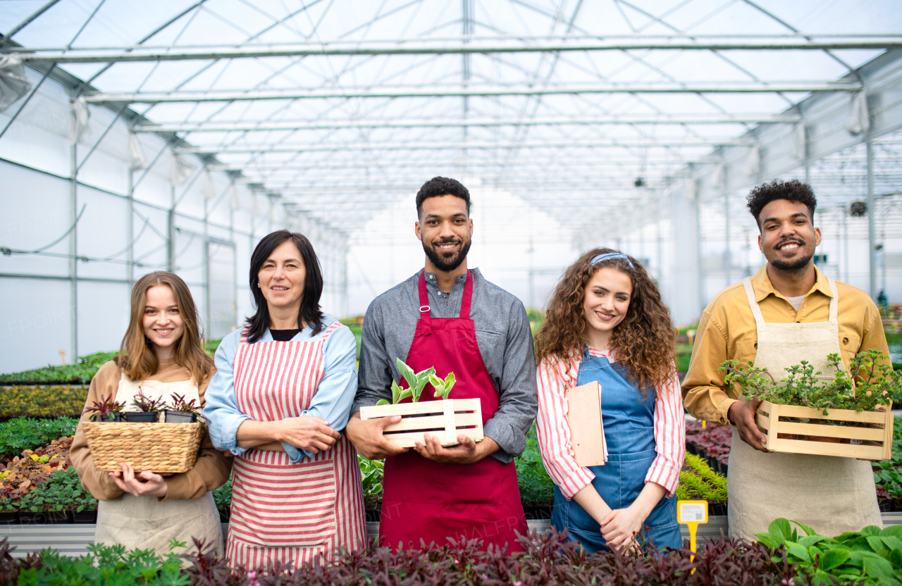 A portrait of people working in greenhouse in garden center, looking at camera.