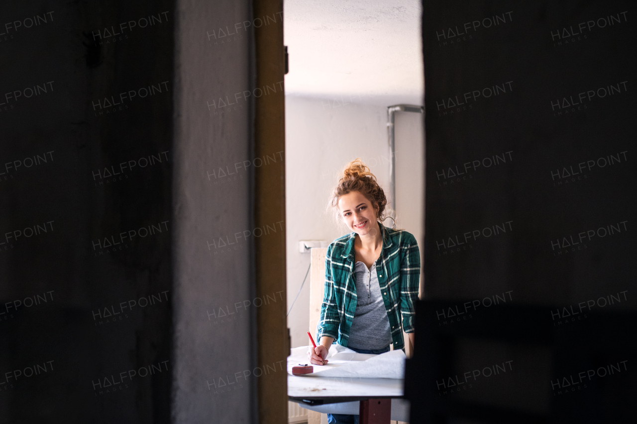 Small business of a young woman. Beautiful young woman worker in a workroom. Female carpenter sketching a project.