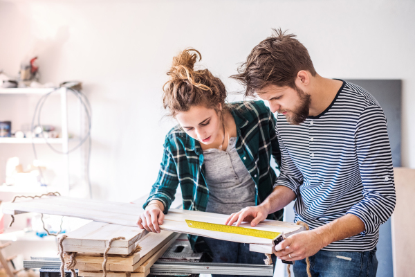 Small business of a young couple. Man and woman worker in the carpenter workroom.