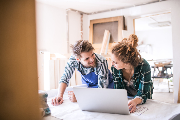 Man and woman worker with laptop in the carpenter workroom. Young couple working together.