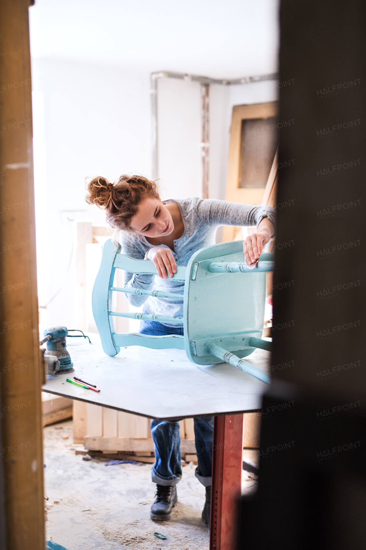 Small business of a young woman. Beautiful young woman worker in carpenter workroom. Old furniture restoration.