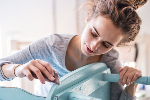 Small business of a young woman. Beautiful young woman worker in carpenter workroom. Old furniture restoration. Close up.