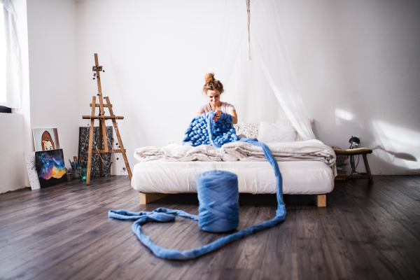 Small business of a young woman. A beautiful woman hand-knitting a woollen blanket.