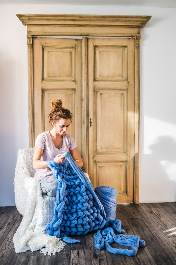 Small business of a young woman. Young woman hand-knitting a woollen blanket.