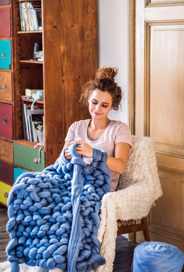 Small business of a young woman. Young woman hand-knitting a woollen blanket.