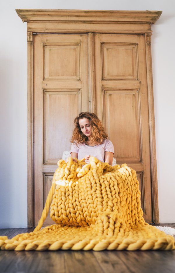 Small business of a young woman. Young woman hand-knitting a woollen blanket.