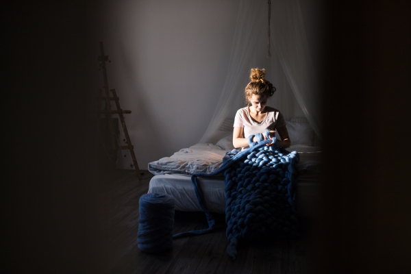 Small business of a young woman. Young woman hand-knitting a woollen blanket.