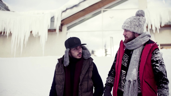 Two young friends on a walk outdoors in snow in winter, talking. Slow motion.