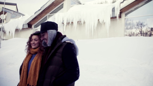 Young couple on a walk outdoors in snow in winter, talking. Slow motion.