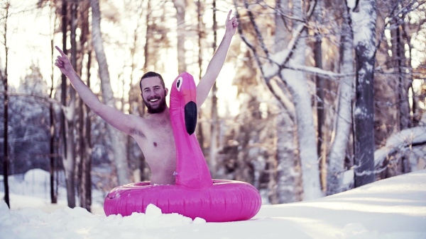 A portrait of topless young man outdoors in snow in winter forest, having fun. Slow motion.