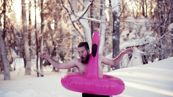 A portrait of topless young man outdoors in snow in winter forest, having fun. Slow motion.