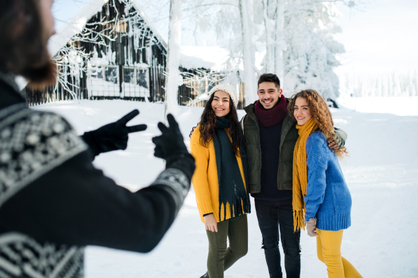 A group of young cheerful friends on a walk outdoors in snow in winter, talking.