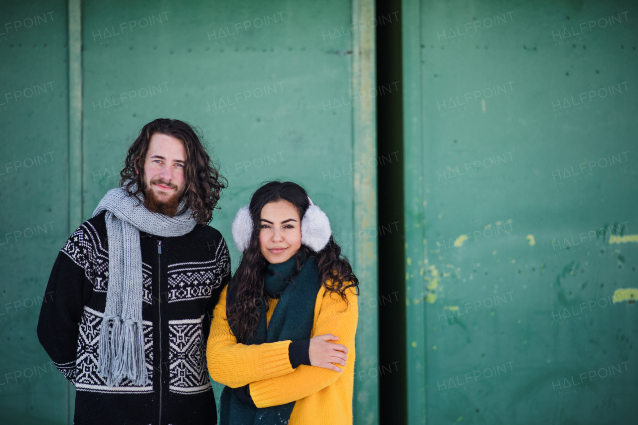 A portrait of young couple standing outdoors in winter, looking at camera. Copy space.