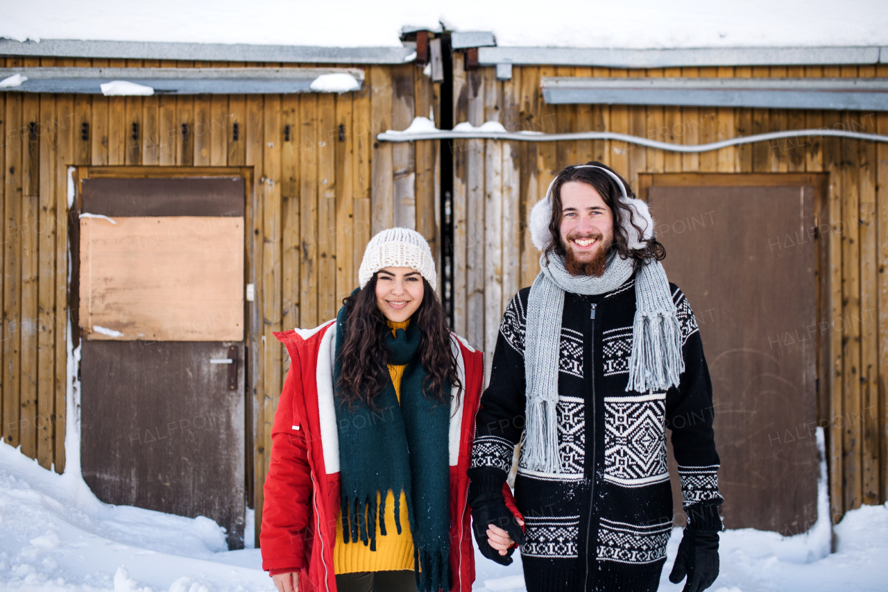 A portrait of young couple standing outdoors in winter, looking at camera.