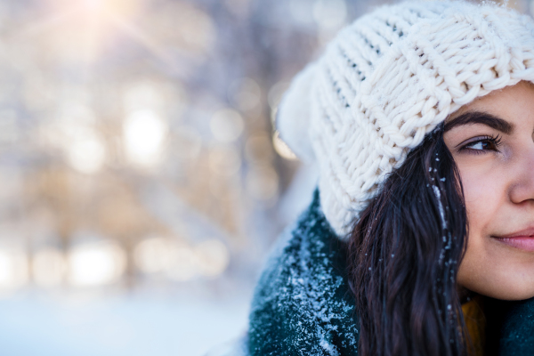 A midsection of a young woman standing outdoors in snowy winter forest. Copy space.