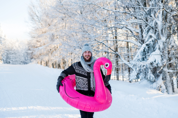 A portrait of young man outdoors in snow in winter forest, having fun.