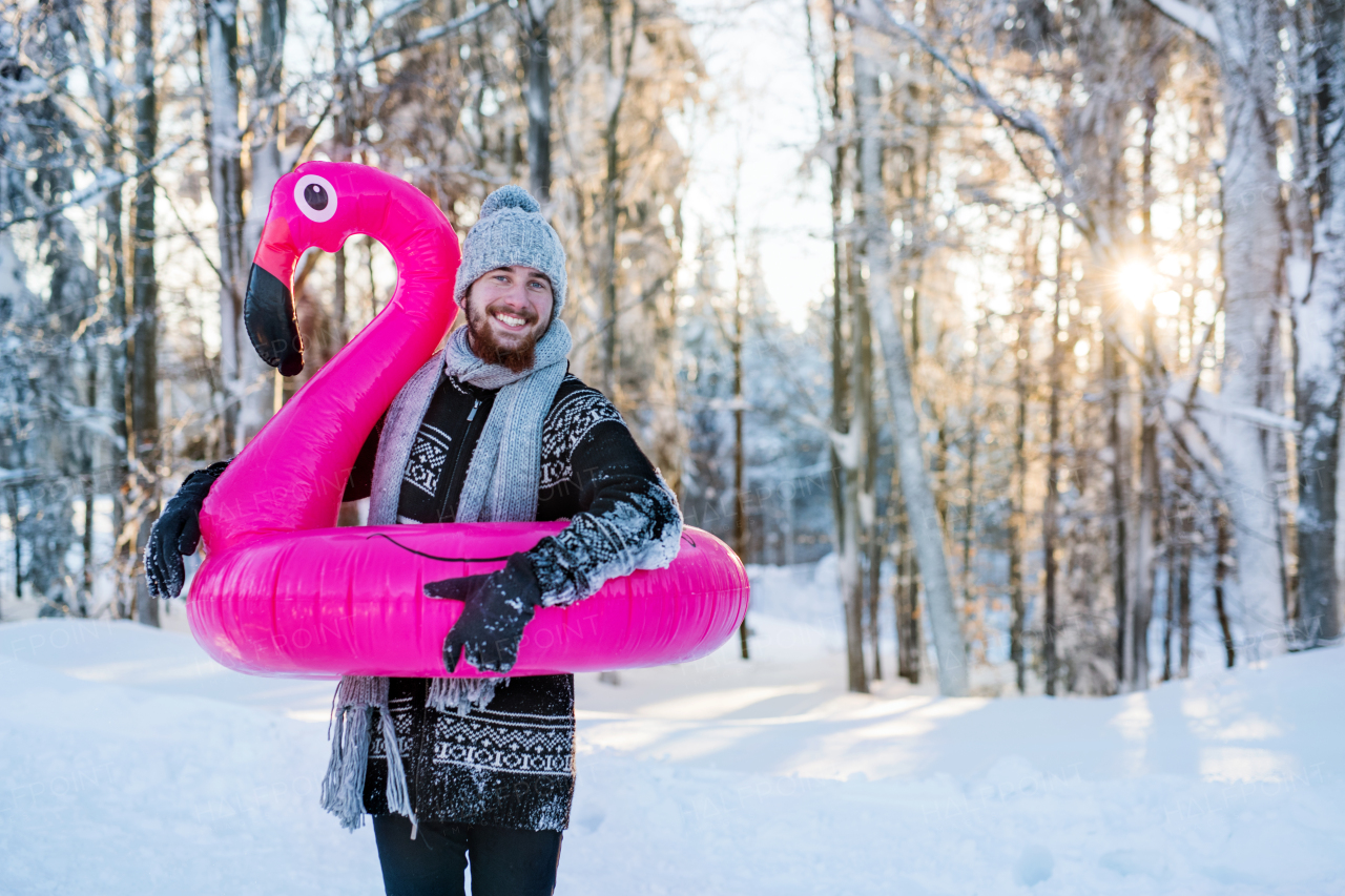 A portrait of young man outdoors in snow in winter forest, having fun.