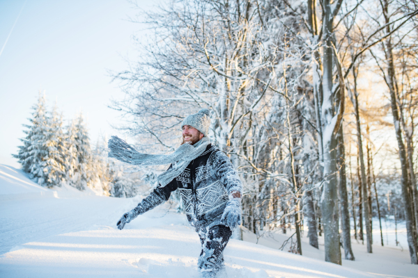 Young man having fun outdoors in winter, jumping in snow.