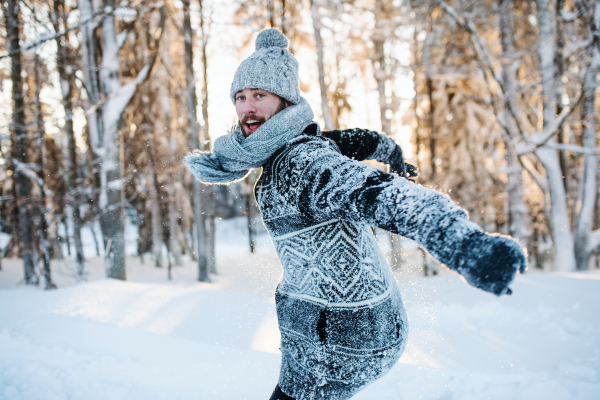 Young man having fun outdoors in winter, jumping in snow.