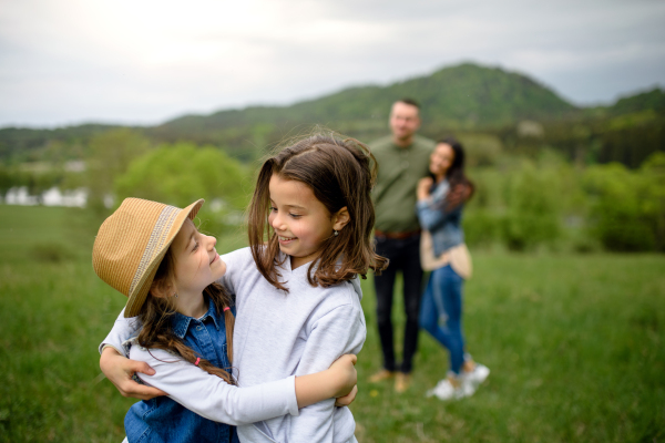 Happy family with two small daughters walking outdoors in spring nature, talking.